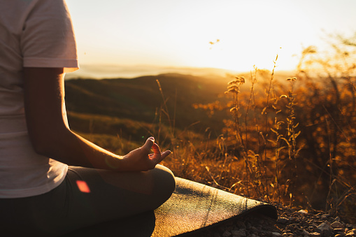 Woman hand in lotus position closeup. Zen meditation. Healthy lifestyle and yoga concept. Background of warm sunlight and mountain view. Empty place.