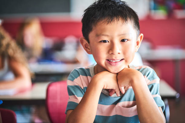 istock Smiling boy sitting in classroom at school 1224088053