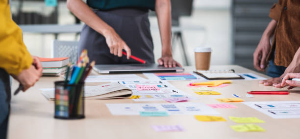 Close up ux developer and ui designer brainstorming about mobile app interface wireframe design on table with customer brief and color code at modern office.Creative digital development agency.panning Close up ux developer and ui designer brainstorming about mobile app interface wireframe design on table with customer brief and color code at modern office.Creative digital development agency.panning council flat stock pictures, royalty-free photos & images