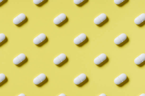 istock Pattern of white pills on a yellow background. Hard light. Paper background 1224090921