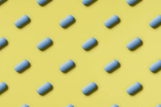 istock Pattern of blue pills on a yellow background. Hard light. Paper background 1224090930