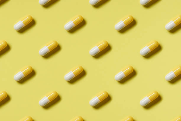 istock Pattern of yellow and white pills on a yellow background. Hard light. Paper background 1224090933