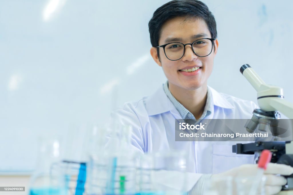 zblízka mladý asijský vědec pomocí mikroskopu k výzkumu nebo záznamu a analýze výsledků vědeckého experimentu s virovými buňkmi v laboratoři pro zdravotní péči a farmaceutický koncept - Bez autorských poplatků Antibiotikum Stock fotka