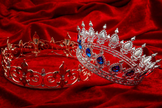 istock Royal authority, monarchy and ruling class concept with princess or queen silver crown with decorative sapphire gems and a king gold crowns with diamond gemstones isolated on red velvet background 1224091166