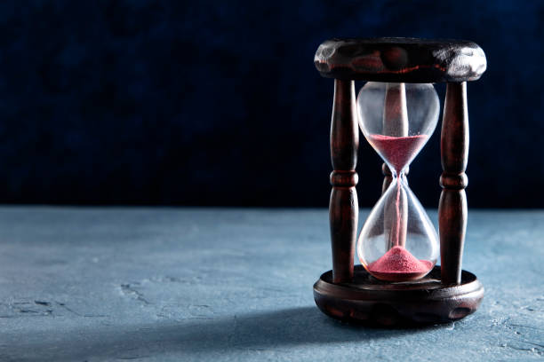 istock Time concept. An hourglass with sand falling through, on a dark background with a place for text 1224091298