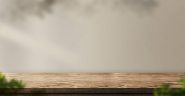 istock wood table background with sunlight window create leaf shadow on wall with blur indoor green plant foreground.panoramic banner mockup for display of product,warm tone lights 1224092274