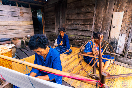 Craftsmen of Thai indigo cotton. Older women are preparing to make indigo-dyed cotton. Thai old woman shows weaving spinning natural colorful threads or yarn.