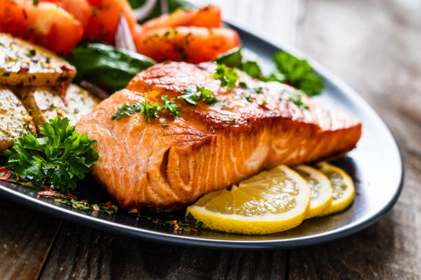 istock Fried salmon steak, fried potatoes and vegetables on wooden background 1224093092