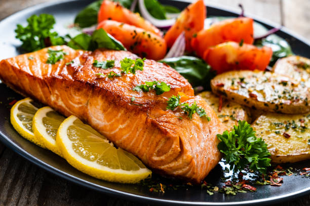 istock Fried salmon steak, fried potatoes and vegetables on wooden background 1224093172