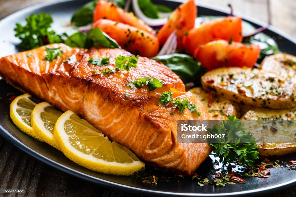 Fried salmon steak, fried potatoes and vegetables on wooden background Barbecued salmon, fried potatoes and vegetables on wooden background Grilled Salmon Stock Photo