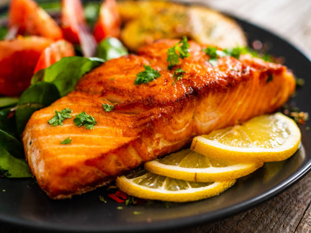 istock Fried salmon steak, fried potatoes and vegetables on wooden background 1224093316