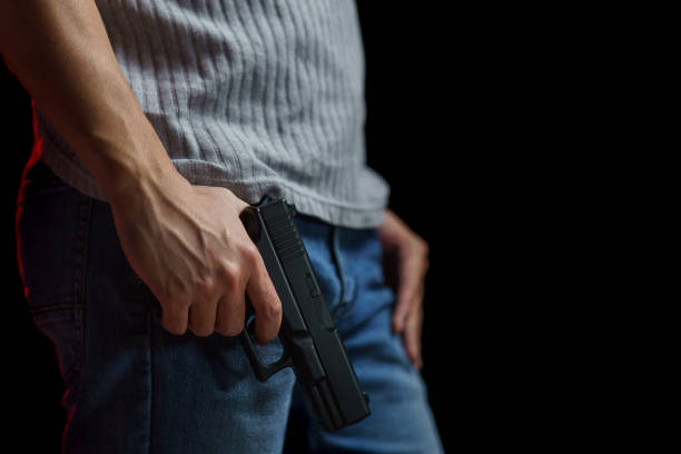 istock Man holding a gun side him on black background. 1224094421