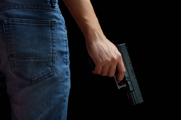 istock Man holding a gun side him on black background. 1224094563