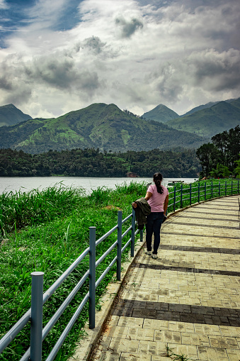 girl looking at pristine lake with mountain background and beautiful hiking trails image is taken at banasura sagar dam wayanad kerala india. the natural beauty of this place is amazing.