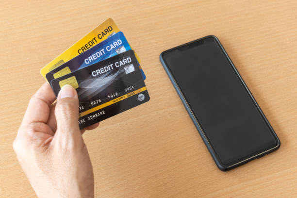 homme retenant des cartes de crédit et le smartphone. achats en ligne sur internet à l’aide d’un smartphone - internet e mail paying credit card photos et images de collection