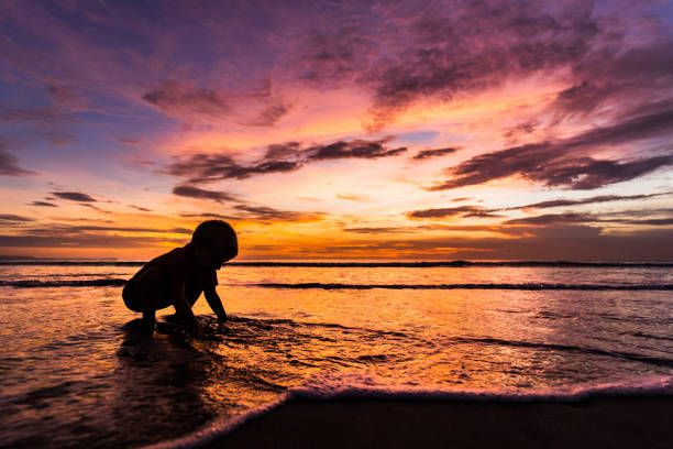 A silhouette of a boy playing in Lake Michigan at sunset