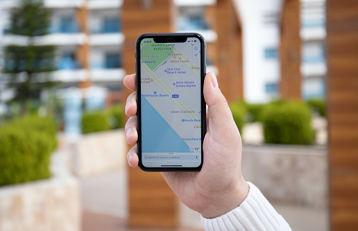 Alanya, Turkey - March 31, 2020: Man hand holding iPhone 11 with Apple map on the screen. iPhone was created and developed by the Apple inc.
