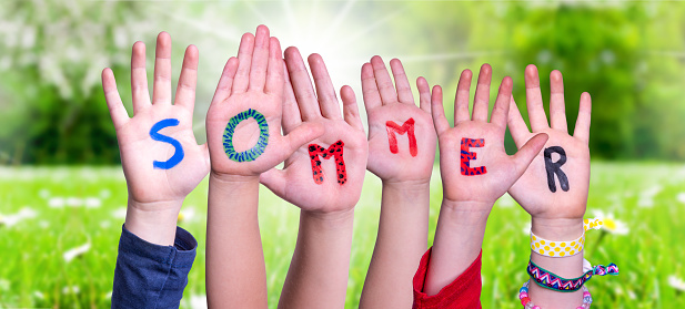 Children Hands Building Colorful German Word Sommer Means Summer. Sunny Green Grass Meadow As Background