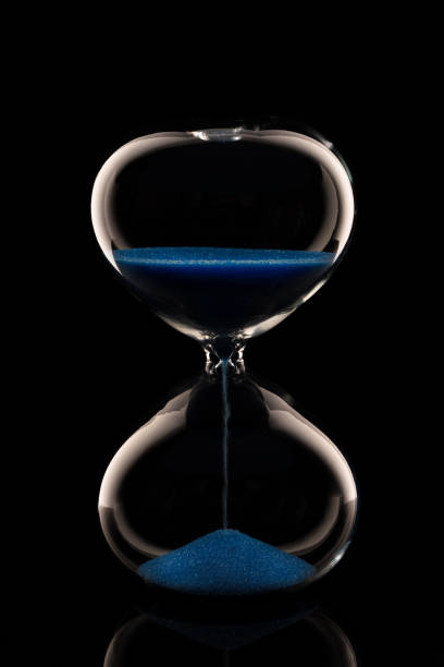 istock blue sand hourglass on black background 1224116968