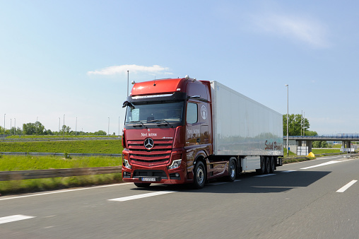 Zagreb, Croatia - May 09, 2020: New Mercedes Actros truck in beautiful red colour. Mercedes Actros with trailer in motion. Heavy-Duty Truck