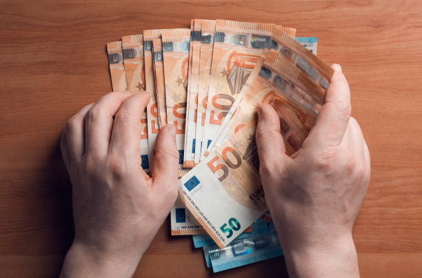 istock Man gather euro banknotes from a wooden table 1224122576