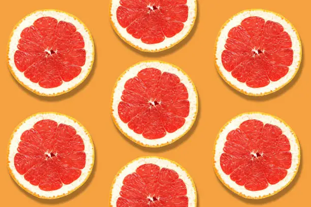 Fresh slices of grapefruit close-up on a yellow-mustard color background. Top view, flat lay