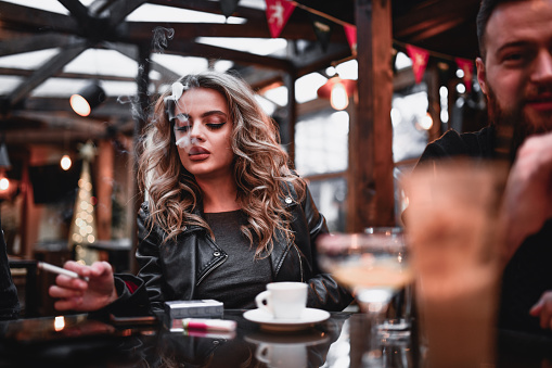 Female Drinking Coffee And Smoking Cigarettes While Enjoying Time Spent With Friends