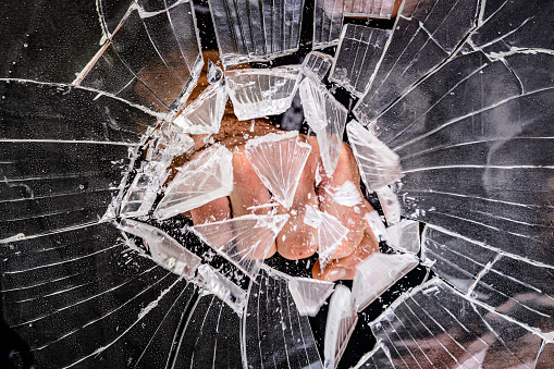 Cracked glass texture on black background. Smashed glass object with shards. Broken glass fragments on black wallpaper. Abstract shattered glass concept