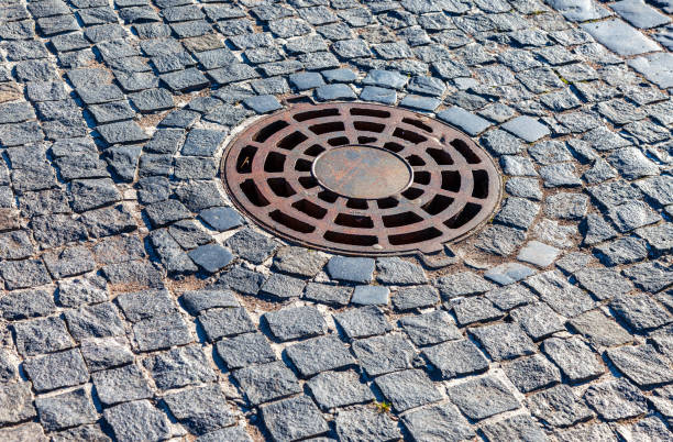 Rusty metal manhole cover on urban pavement road. Round drainage sewer manhole