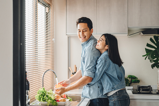Amantes de pareja asiáticos se abrazan en la cocina mientras cocinan en casa photo