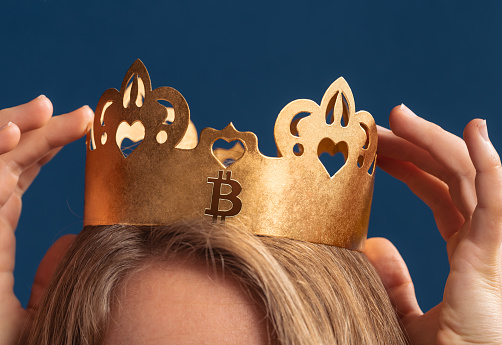 Young woman wearing gold crown with Bitcoin symbol printed on it