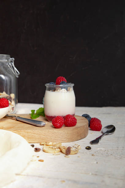 istock Breakfast with white yogurt with fresh raspberries, blueberries and muesli on serving board on rustic table. Vertical image 1224130955
