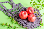 Food delivery. Red apples on a hand-tied grid on a green background. Eco-concept. Reuse, reduction, processing.