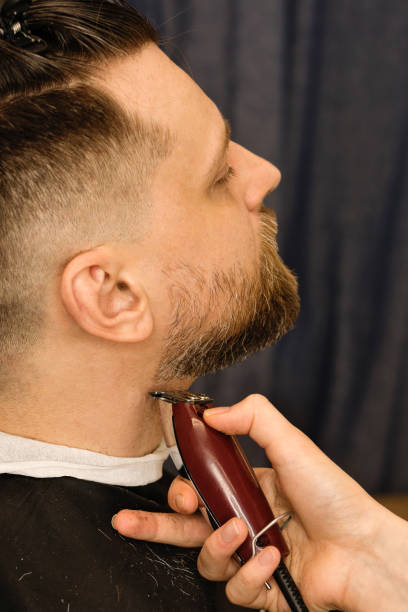 istock Barber trimming beard with electric razor 1224135676