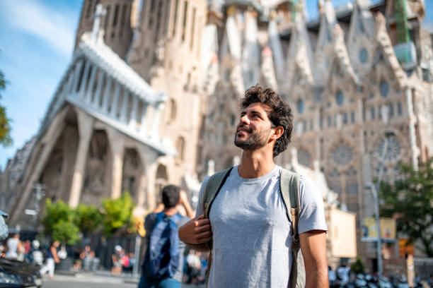 Mid Adult Male Tourist with Smart Phone in Barcelona Low angle view of 30 year old Hispanic male tourist using smart phone for sightseeing guidance with Sagrada Familia in background. city break photos stock pictures, royalty-free photos & images