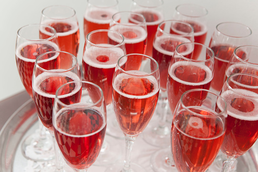 Tray of glasses filled with red Champagne