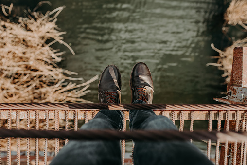 Men's feet in shoes on the edge of a clipping bridge
