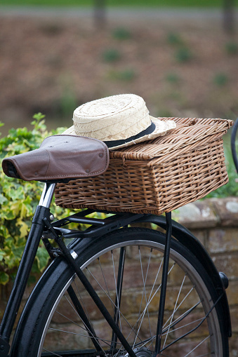 Straw hat sitting on the top of a basket on the back of a bicycle