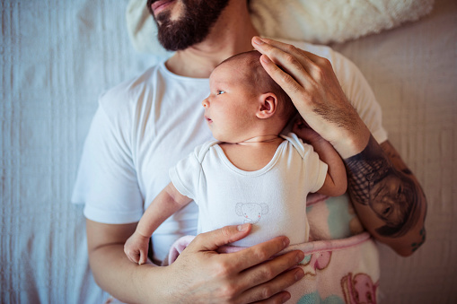 Newborn girl and father lying in bed