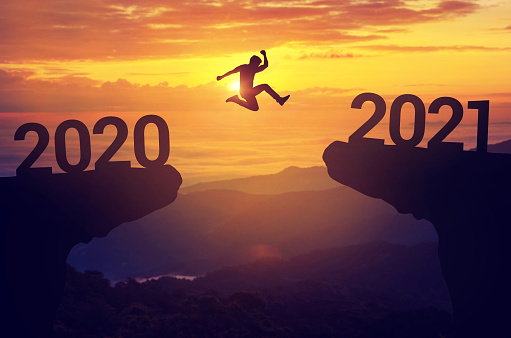 Silhouette hombre saltar entre 2020 y 2021 años con fondo de puesta de sol, concepto de año nuevo success. photo
