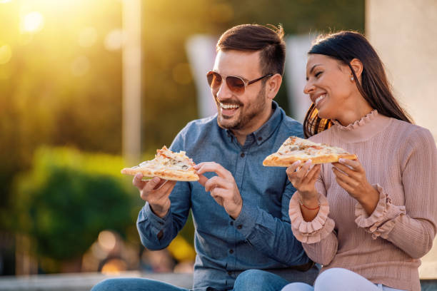 Picture of happy young couple eating pizza outdoors stock photo