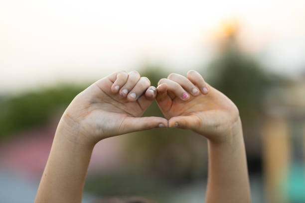 istock Child making heart shape with hand outdoors during sunset 1224144316