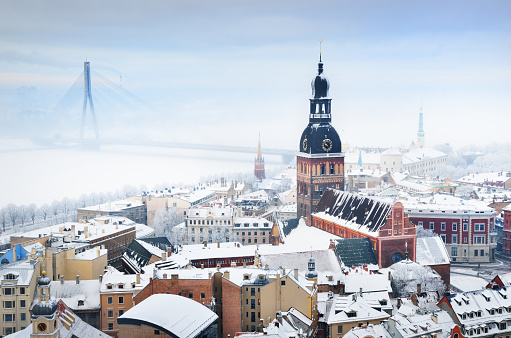 Panoramic view of the Riga old town and Daugava river from St. Peter's Church on a clear winter day. Morning fog and snow-covered houses. Latvia