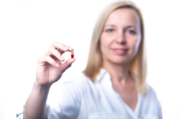 istock Smiling woman shows a capsule tablet. Focus on the capsule. 1224147537