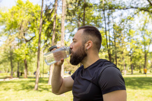istock Athletic man drinking water after running in the park 1224148917