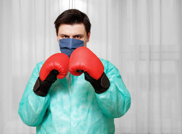 medico maschio con boxe guanti rossi pronti a combattere con il coronavirus - rubber sports glove equipment isolated foto e immagini stock