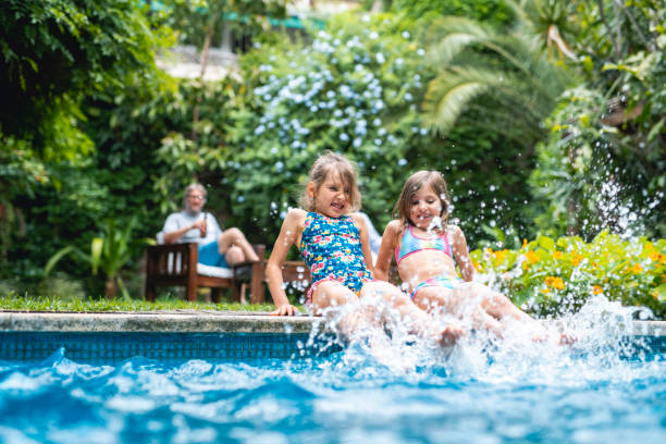 istock Excited Young Sisters Kicking Water in Swimming Pool 1224153025