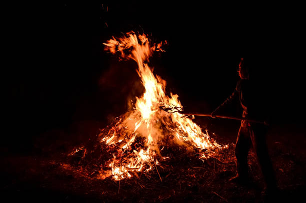 istock A man throws dry leaves into a large fire, night. 1224153083