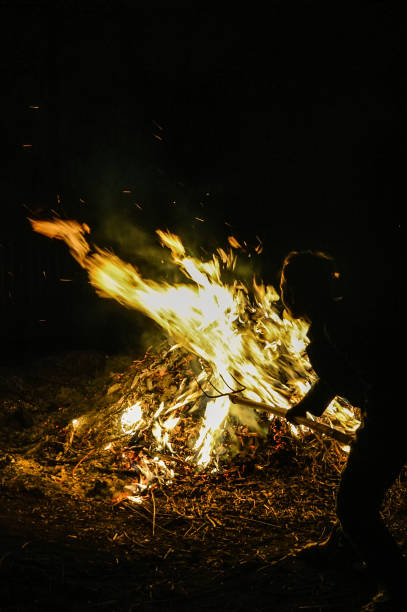 istock A man throws dry leaves into a large fire, night. 1224153087