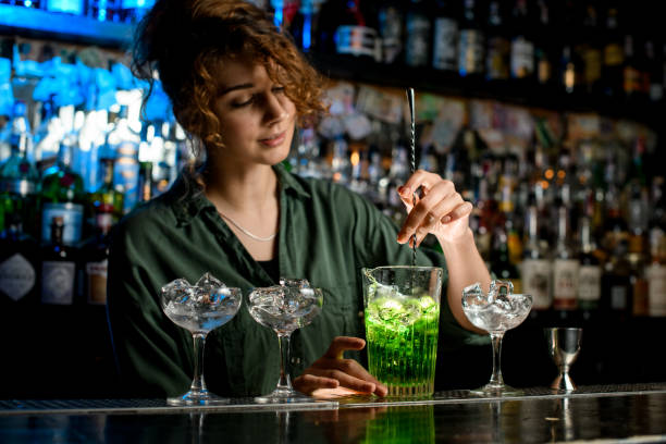 istock Nice woman bartender actively mixes cocktail in glass with ice. 1224154302